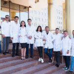 A group of European medical students presented outdoor against the university door on the steps.